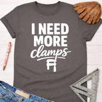 Women's funny woodworking graphic tee shirt for female woodworkers, makers, and DIY builders — Sawdust & Ponytails. Dark gray cotton t-shirt with "I NEED MORE clamps" text and clamp graphic.