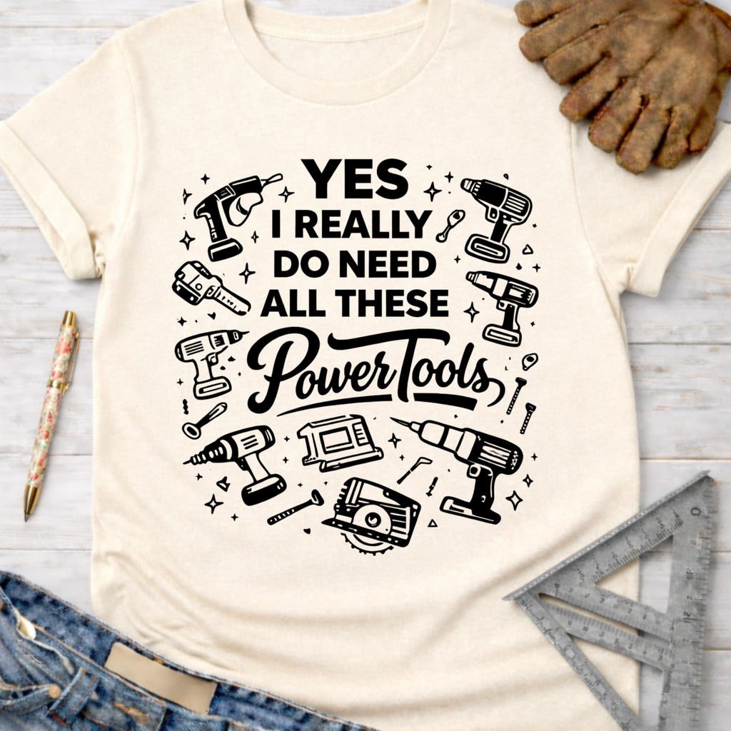 Women's funny woodworking graphic tee shirt for female woodworkers, makers, and DIY builders — Sawdust & Ponytails. Cream t-shirt with "YES I REALLY DO NEED ALL THESE Power Tools" and tool graphics.