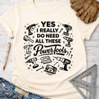 Women's funny woodworking graphic tee shirt for female woodworkers, makers, and DIY builders — Sawdust & Ponytails. Cream t-shirt with "YES I REALLY DO NEED ALL THESE Power Tools" and tool graphics.