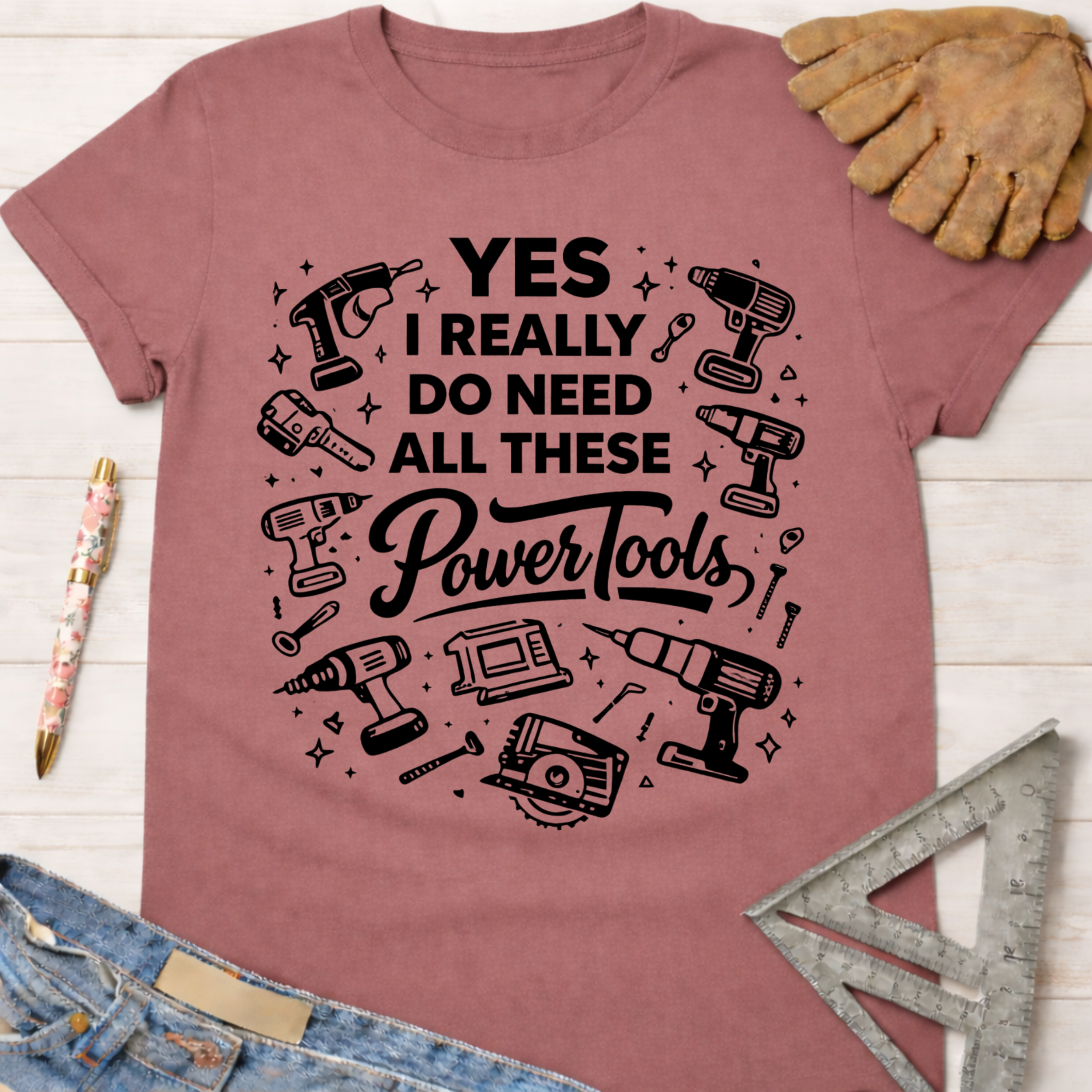 Women's funny woodworking graphic tee shirt for female woodworkers, makers, and DIY builders — Sawdust & Ponytails. Mauve pink t-shirt with "YES I REALLY DO NEED ALL THESE Power Tools" and tool graphics.