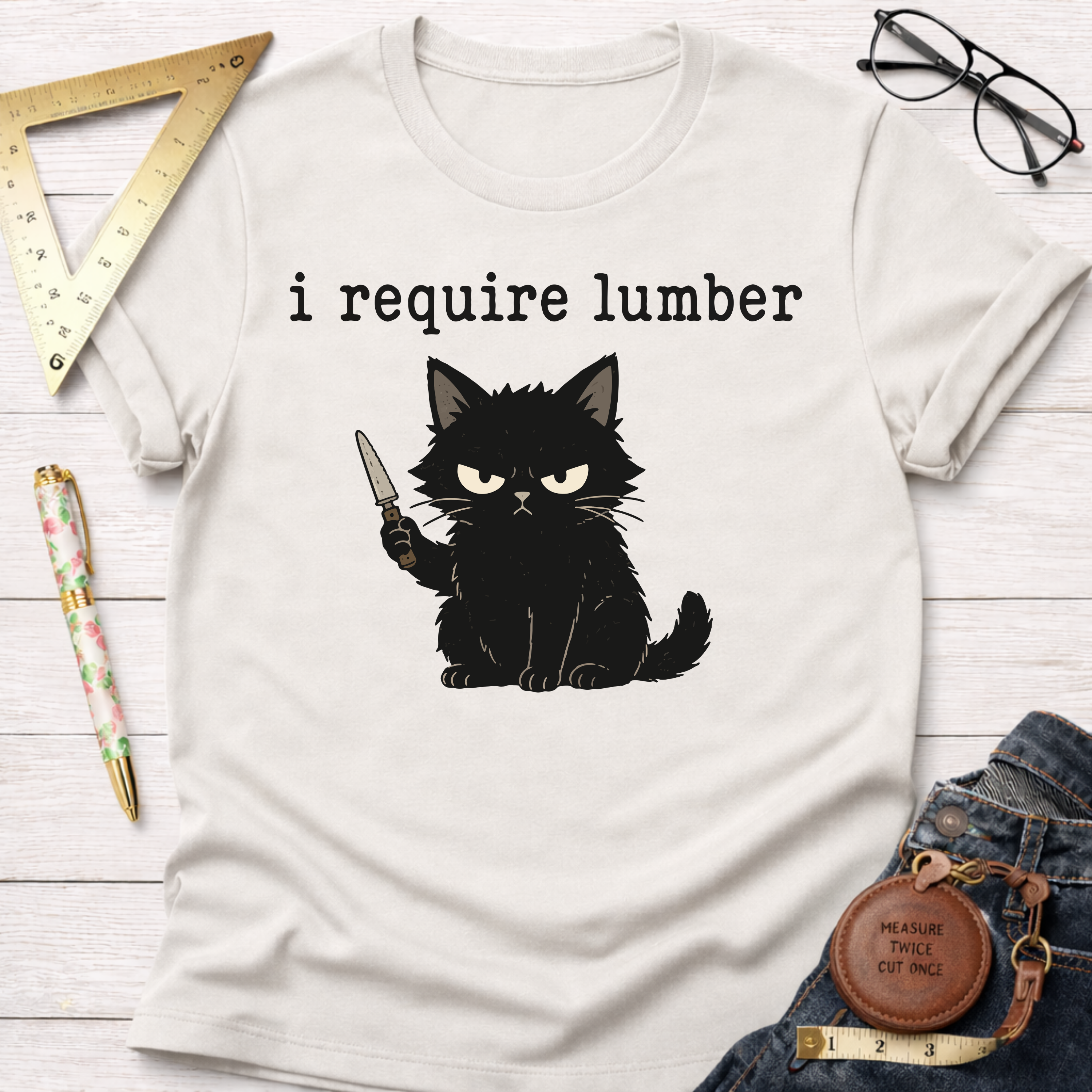 White cotton t-shirt with an angry black cat holding a knife and "i require lumber" text.