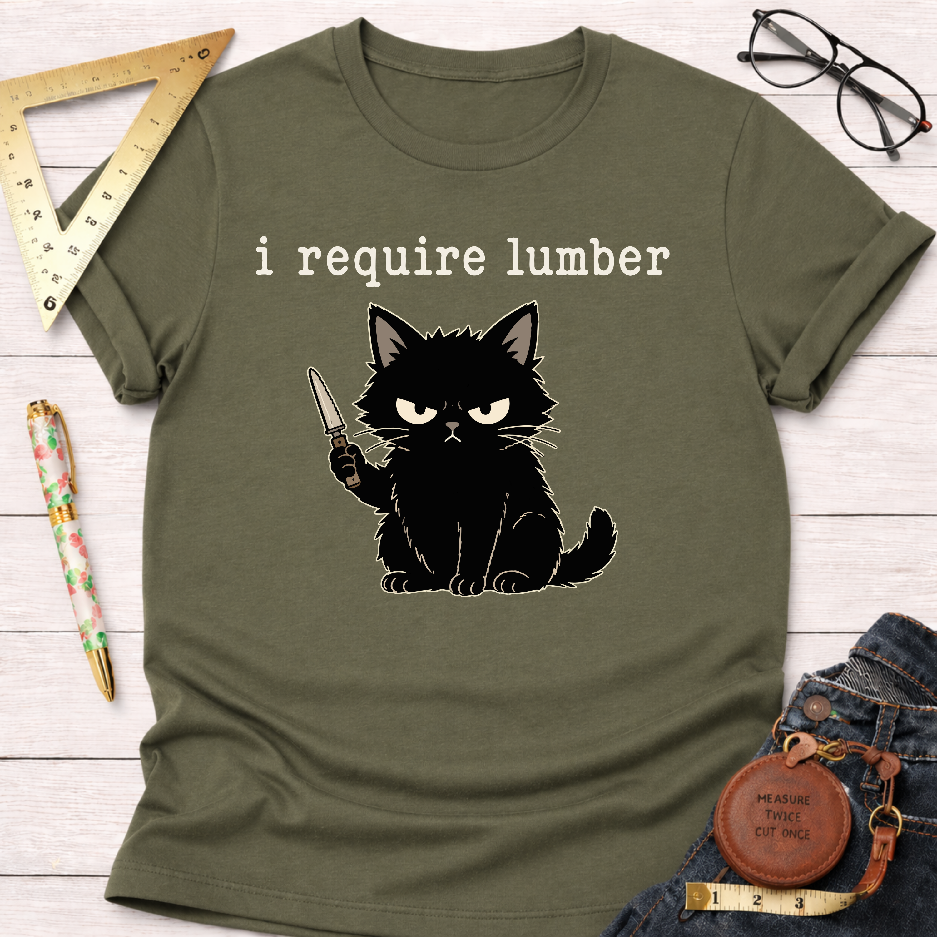 Olive green t-shirt with an angry black cat holding a knife and "i require lumber" text.