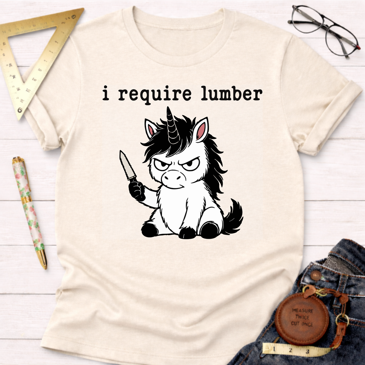 Cream t-shirt with "i require lumber" text and an angry unicorn holding a knife.