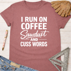 Women's funny woodworking graphic tee shirt for female woodworkers, makers, and DIY builders — Sawdust & Ponytails. Mauve t-shirt with "I RUN ON COFFEE Sawdust AND CUSS WORDS" in white text.
