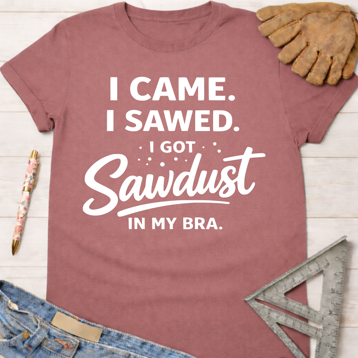 Women's funny woodworking graphic tee shirt for female woodworkers, makers, and DIY builders — Sawdust & Ponytails. Mauve short-sleeve tee with "I Came. I Sawed. I Got Sawdust In My Bra." in white text.