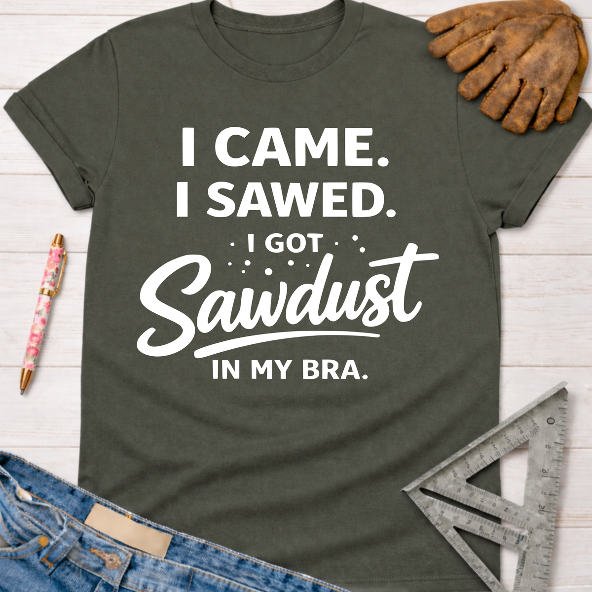 Women's funny woodworking graphic tee shirt for female woodworkers, makers, and DIY builders — Sawdust & Ponytails. Dark gray tee with "I Came. I Sawed. I Got Sawdust In My Bra." text.