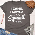 Women's funny woodworking graphic tee shirt for female woodworkers, makers, and DIY builders — Sawdust & Ponytails. Dark gray cotton tee with "I Came. I Sawed. I Got Sawdust In My Bra." text.