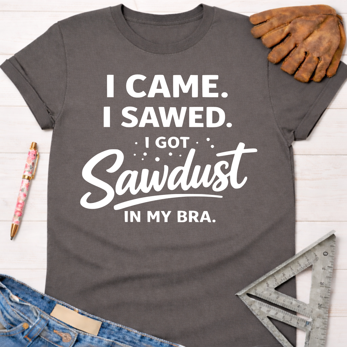 Women's funny woodworking graphic tee shirt for female woodworkers, makers, and DIY builders — Sawdust & Ponytails. Dark gray cotton tee with "I Came. I Sawed. I Got Sawdust In My Bra." text.