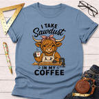 Light blue cotton t-shirt with a cartoon Highland cow wearing an apron, holding coffee, and "I Take Sawdust In My Coffee" text.