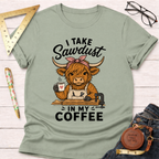 Sage green cotton t-shirt with a cartoon Highland cow wearing an apron, holding coffee, and "I Take Sawdust In My Coffee" text.