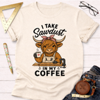 Cream t-shirt with a cartoon Highland cow wearing an apron, holding coffee, and "I Take Sawdust In My Coffee" text.