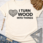 Women's funny woodworking graphic tee shirt for female woodworkers, makers, and DIY builders — Sawdust & Ponytails. Cream t-shirt with "I TURN WOOD INTO THINGS" and a heart-shaped wood grain design.