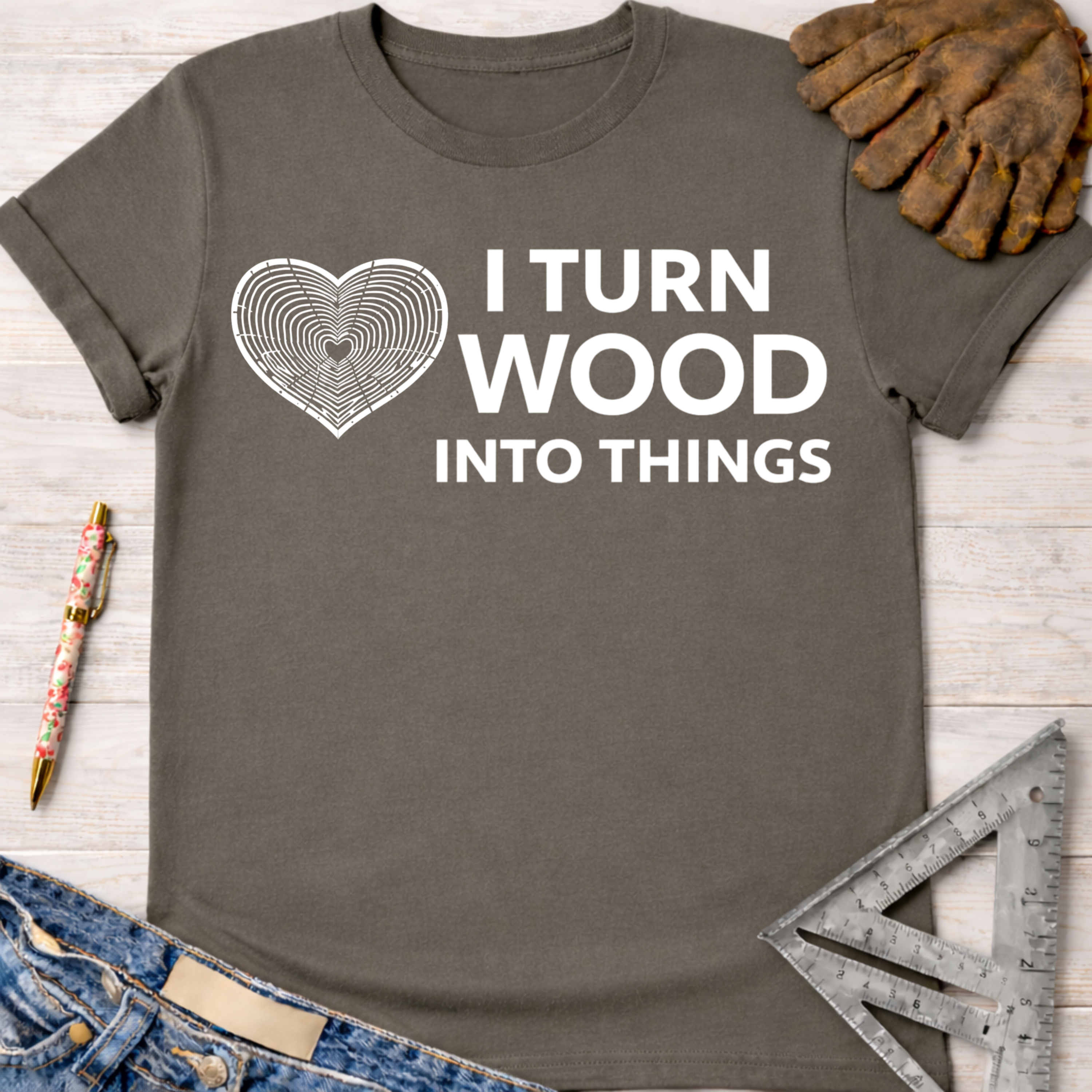 Women's funny woodworking graphic tee shirt for female woodworkers, makers, and DIY builders — Sawdust & Ponytails. Dark gray cotton tee with "I Turn Wood Into Things" text and a heart-shaped wood grain graphic.