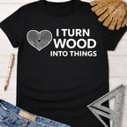 Women's funny woodworking graphic tee shirt for female woodworkers, makers, and DIY builders — Sawdust & Ponytails. Black cotton tee with white "I Turn Wood Into Things" text and wood grain heart design.
