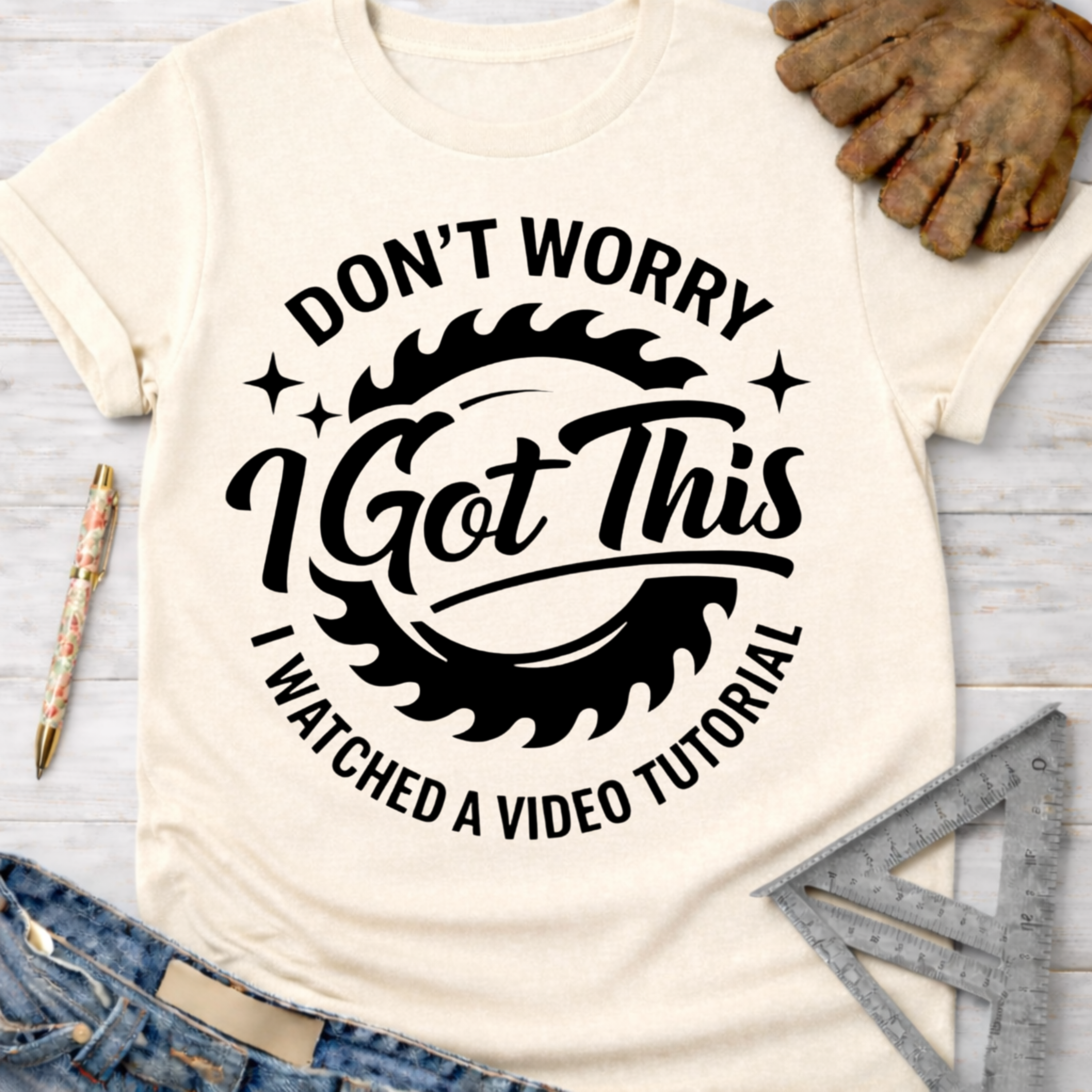 Women's funny woodworking graphic tee shirt for female woodworkers, makers, and DIY builders — Sawdust & Ponytails. Cream t-shirt with "Don't Worry I Got This I Watched A Video Tutorial" text and saw blade graphic.