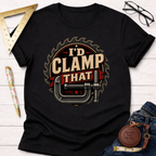 Black "I'd Clamp That" t-shirt with a saw blade and C-clamp graphic, displayed on a white wood surface.