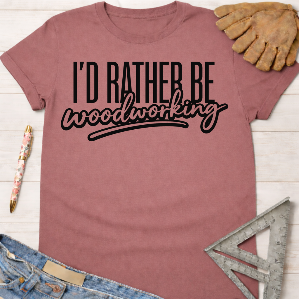 Women's funny woodworking graphic tee shirt for female woodworkers, makers, and DIY builders — Sawdust & Ponytails. Mauve short-sleeve tee with "I'd Rather Be Woodworking" in black text.