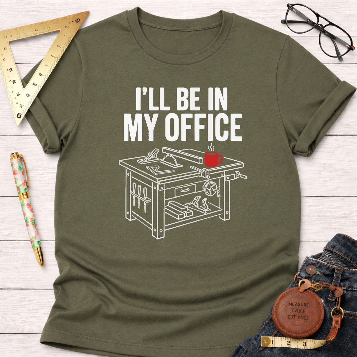 Olive green cotton t-shirt with "I'LL BE IN MY OFFICE" text and a white line art saw table design.