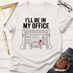 Off-white cotton t-shirt with "I'LL BE IN MY OFFICE" text above a detailed garage workshop illustration.