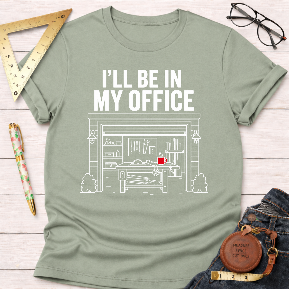 Sage green t-shirt with "I'LL BE IN MY OFFICE" and a white line drawing of a garage workshop.