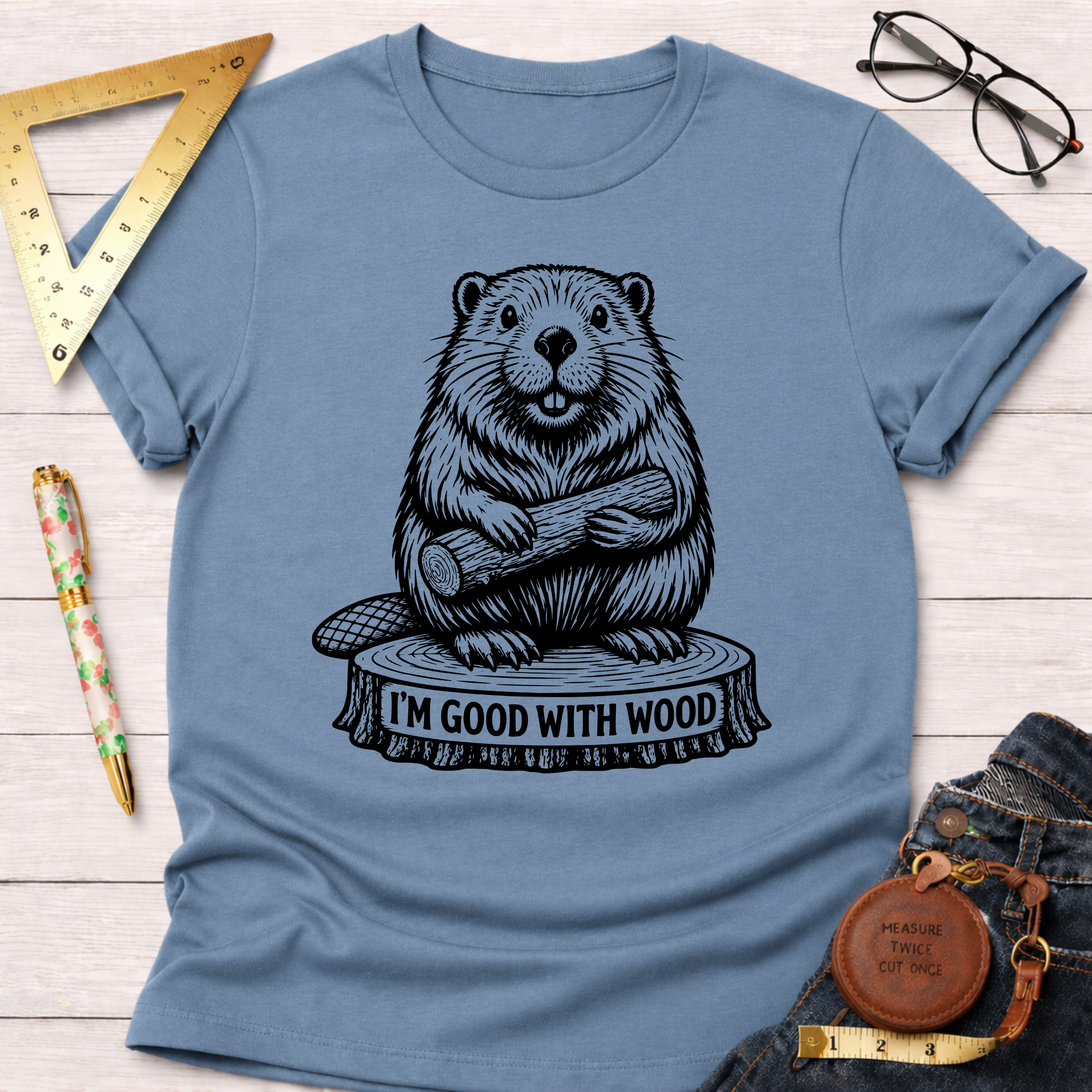 Women's funny woodworking graphic tee shirt for female woodworkers, makers, and DIY builders — Sawdust & Ponytails. Light blue cotton tee with a black beaver holding wood and "I'M GOOD WITH WOOD" graphic.