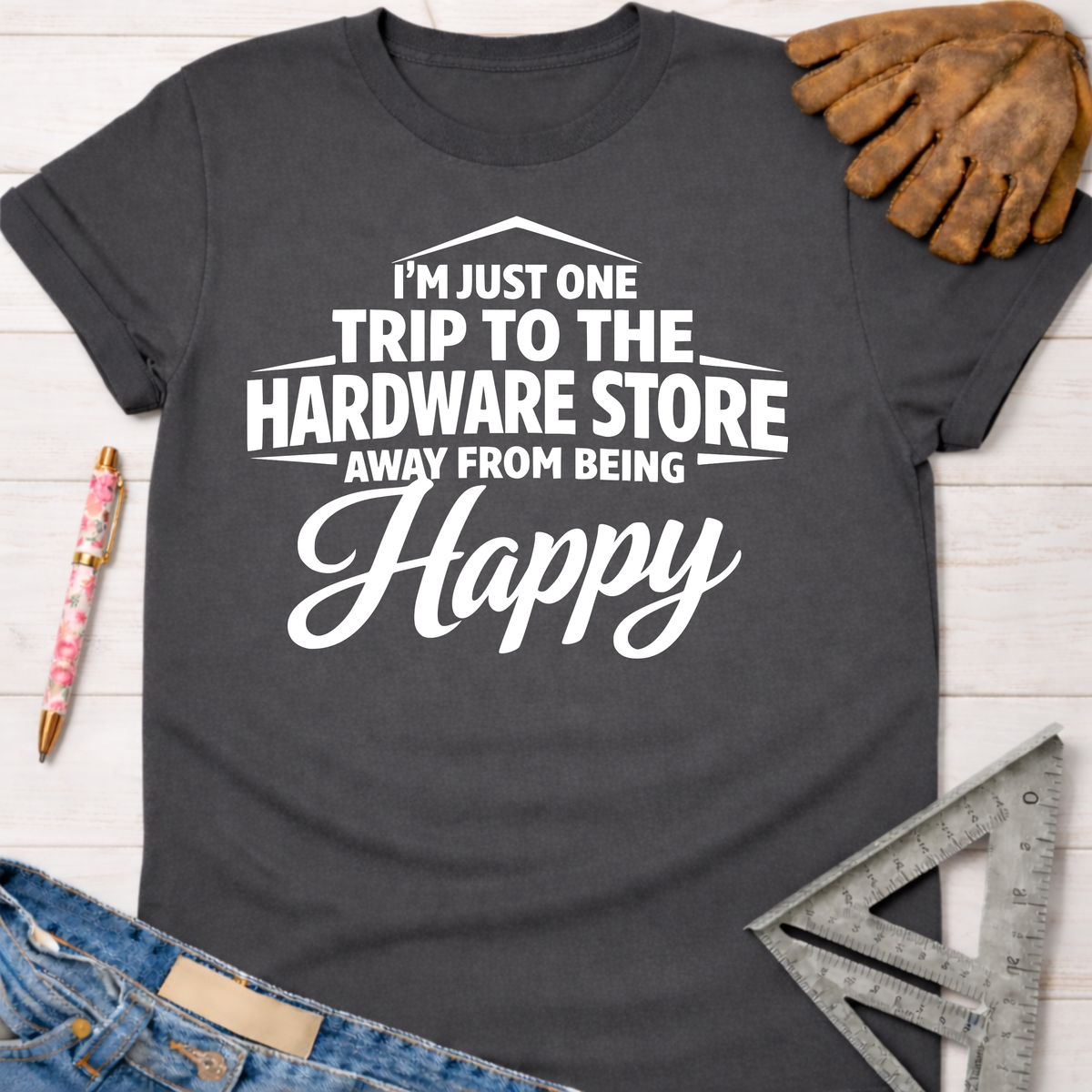 Women's funny woodworking graphic tee shirt for female woodworkers, makers, and DIY builders — Sawdust & Ponytails. Dark gray cotton tee with "I'm Just One Trip To The Hardware Store Away From Being Happy" in white text.
