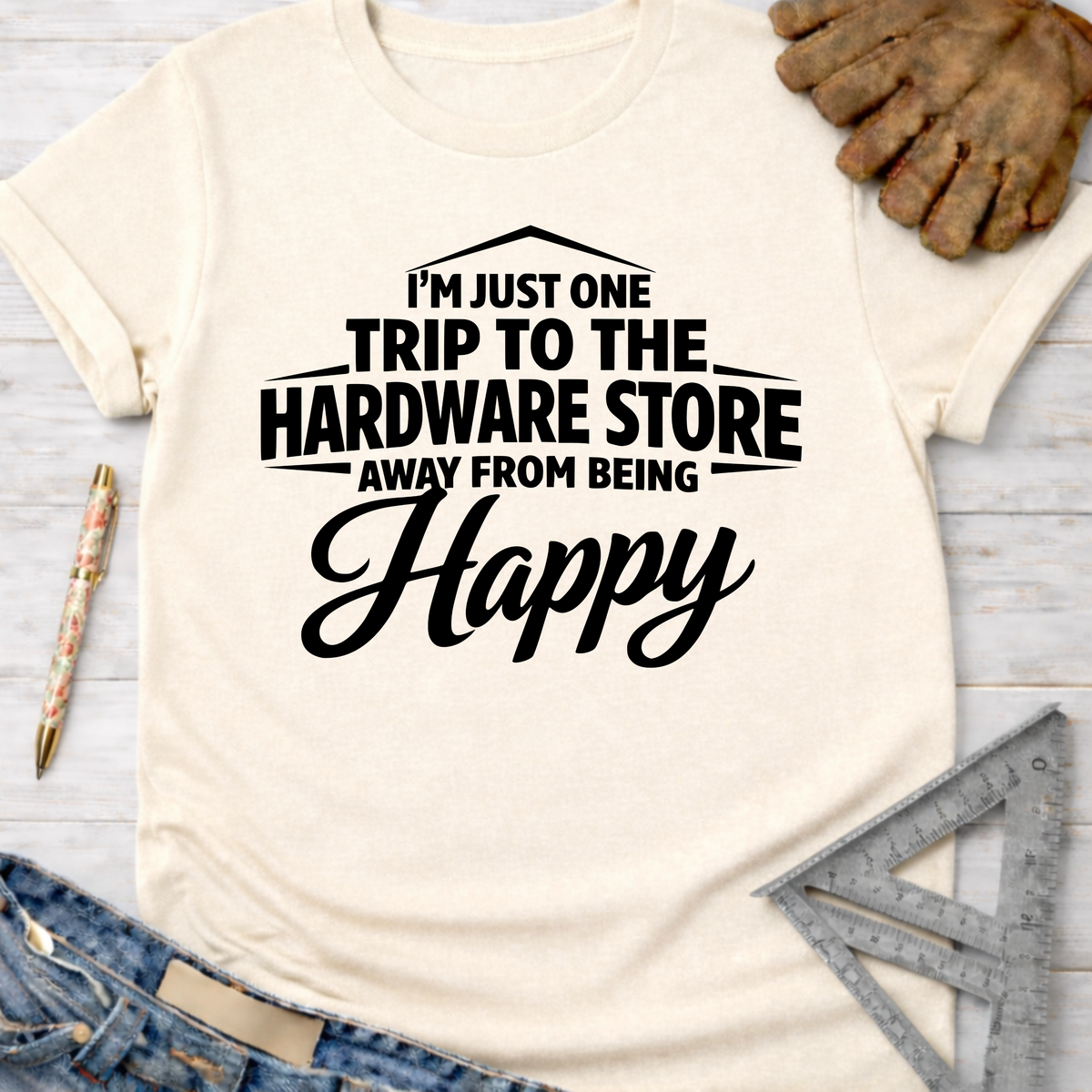 Women's funny woodworking graphic tee shirt for female woodworkers, makers, and DIY builders — Sawdust & Ponytails. Cream t-shirt with "I'm Just One Trip To The Hardware Store Away From Being Happy" in black text.