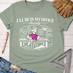 Women's funny woodworking graphic tee shirt for female woodworkers, makers, and DIY builders — Sawdust & Ponytails. Sage green cotton t-shirt with "I'll Be In My Office - Obviously" text and a cartoon female woodworker.