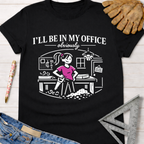 Women's funny woodworking graphic tee shirt for female woodworkers, makers, and DIY builders — Sawdust & Ponytails. Black cotton tee with "I'll Be In My Office" text and a cartoon woman sawing wood.