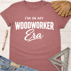Women's funny woodworking graphic tee shirt for female woodworkers, makers, and DIY builders — Sawdust & Ponytails. Mauve short-sleeve tee with "I'm in My Woodworker Era" in white text.