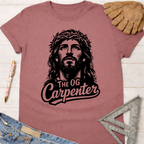 Women's funny woodworking graphic tee shirt for female woodworkers, makers, and DIY builders — Sawdust & Ponytails. Mauve short-sleeve crewneck tee with "Jesus The OG Carpenter" graphic.