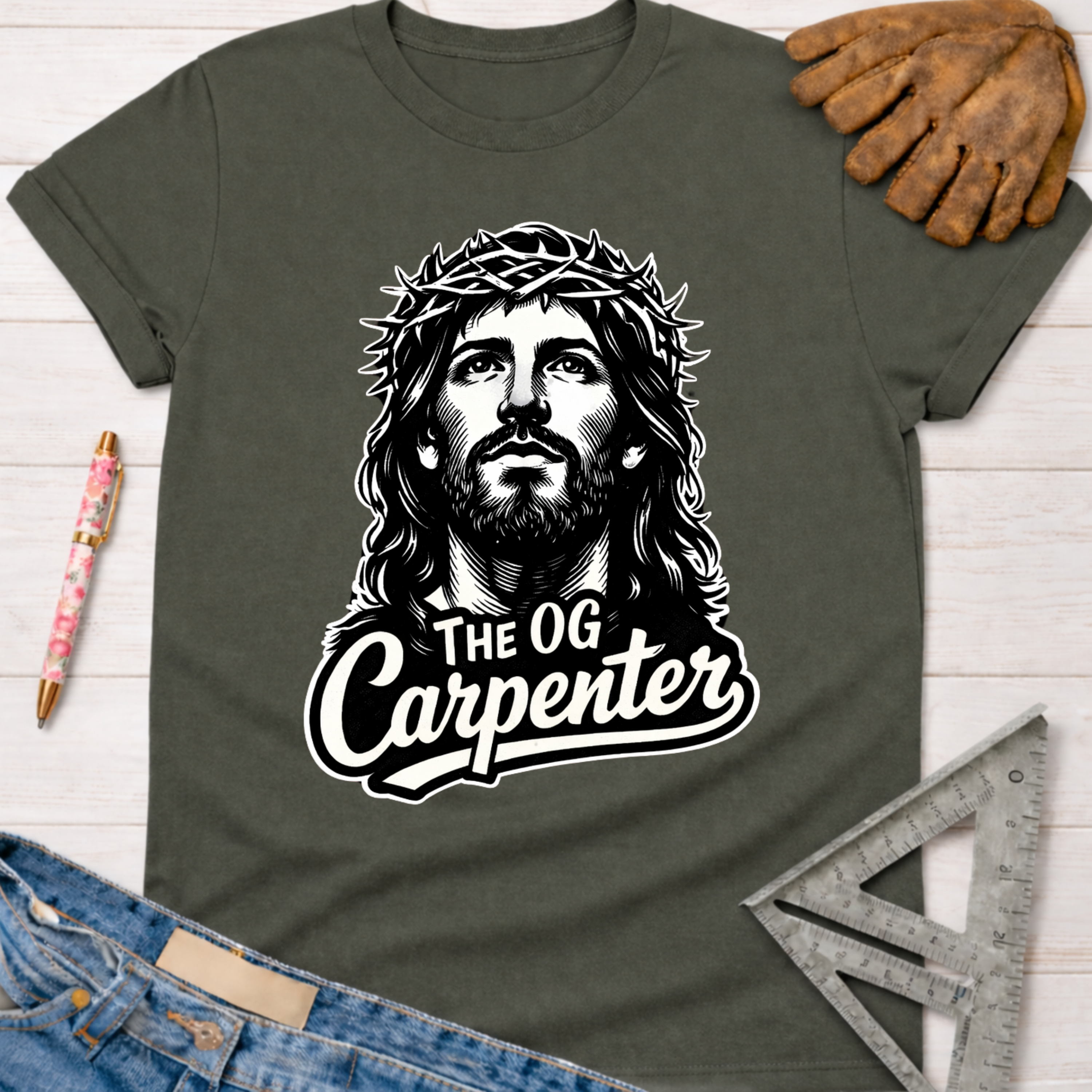 Women's funny woodworking graphic tee shirt for female woodworkers, makers, and DIY builders — Sawdust & Ponytails. Dark gray tee with a black and white graphic of Jesus wearing a crown of thorns and "The OG Carpenter" text.