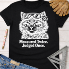 Women's funny woodworking graphic tee shirt for female woodworkers, makers, and DIY builders — Sawdust & Ponytails. Black cotton tee with white "Measured Twice. Judged Once." text and a cat wearing safety glasses.