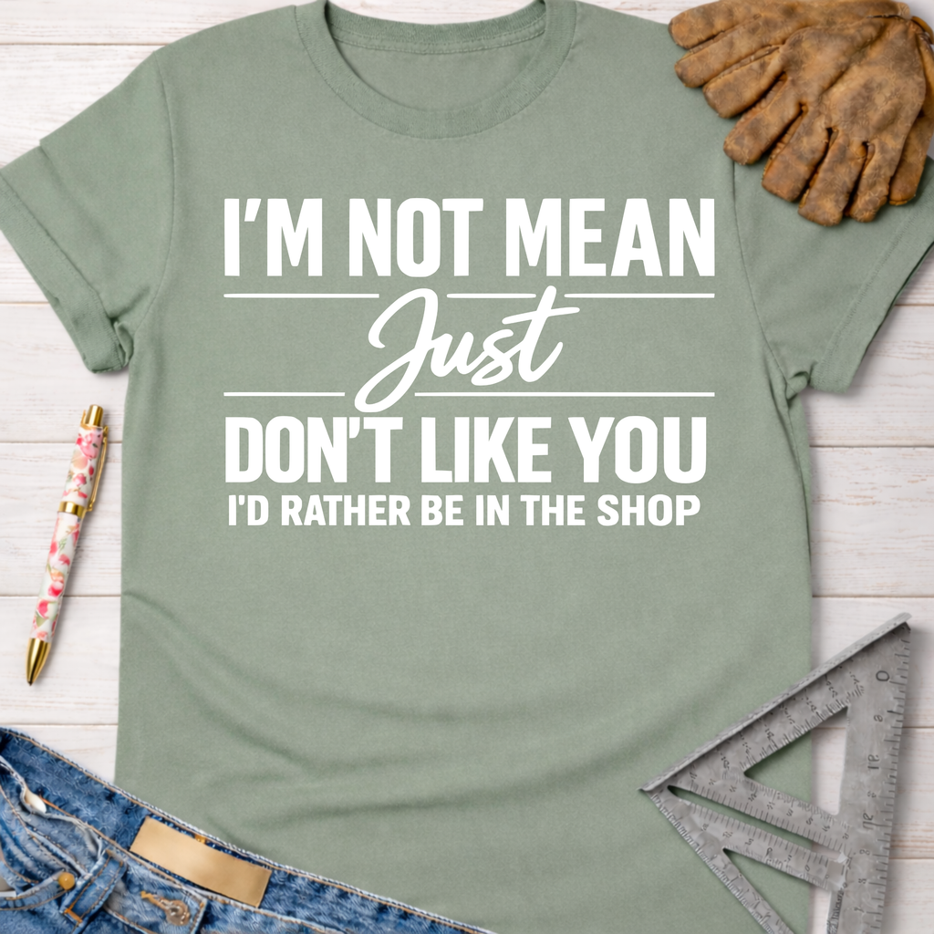 Women's funny woodworking graphic tee shirt for female woodworkers, makers, and DIY builders — Sawdust & Ponytails. Sage green t-shirt with "I'm Not Mean Just Don't Like You I'd Rather Be In The Shop" text.