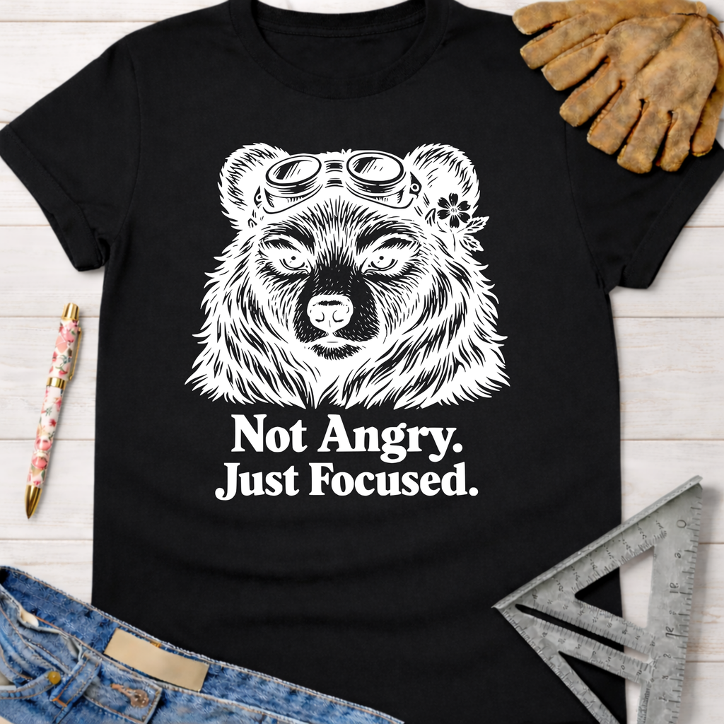 Women's funny woodworking graphic tee shirt for female woodworkers, makers, and DIY builders — Sawdust & Ponytails. Black cotton tee with white bear wearing goggles and "Not Angry. Just Focused." text.