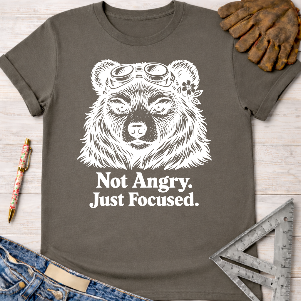 Women's funny woodworking graphic tee shirt for female woodworkers, makers, and DIY builders — Sawdust & Ponytails. Dark gray cotton tee with "Not Angry. Just Focused." text and a bear wearing goggles.