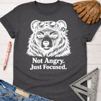 Women's funny woodworking graphic tee shirt for female woodworkers, makers, and DIY builders — Sawdust & Ponytails. Dark gray cotton tee with "Not Angry. Just Focused." text and a bear wearing goggles.