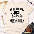 Cream t-shirt with "NO INSTRUCTIONS JUST VIBES AND POWER TOOLS" in black text.