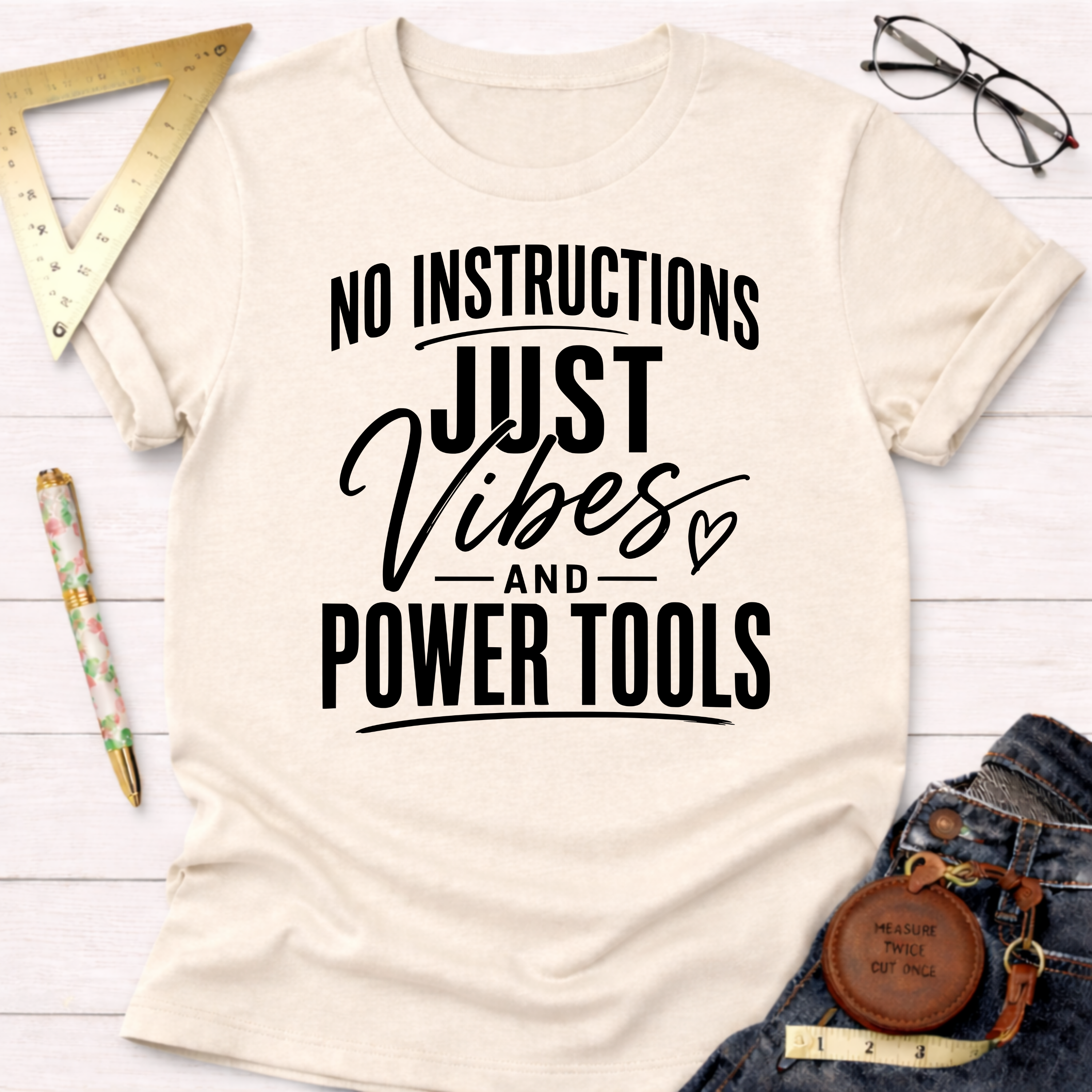Cream t-shirt with "NO INSTRUCTIONS JUST VIBES AND POWER TOOLS" in black text.