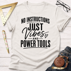 Off-white crew neck t-shirt with "No Instructions Just Vibes And Power Tools" in black text.