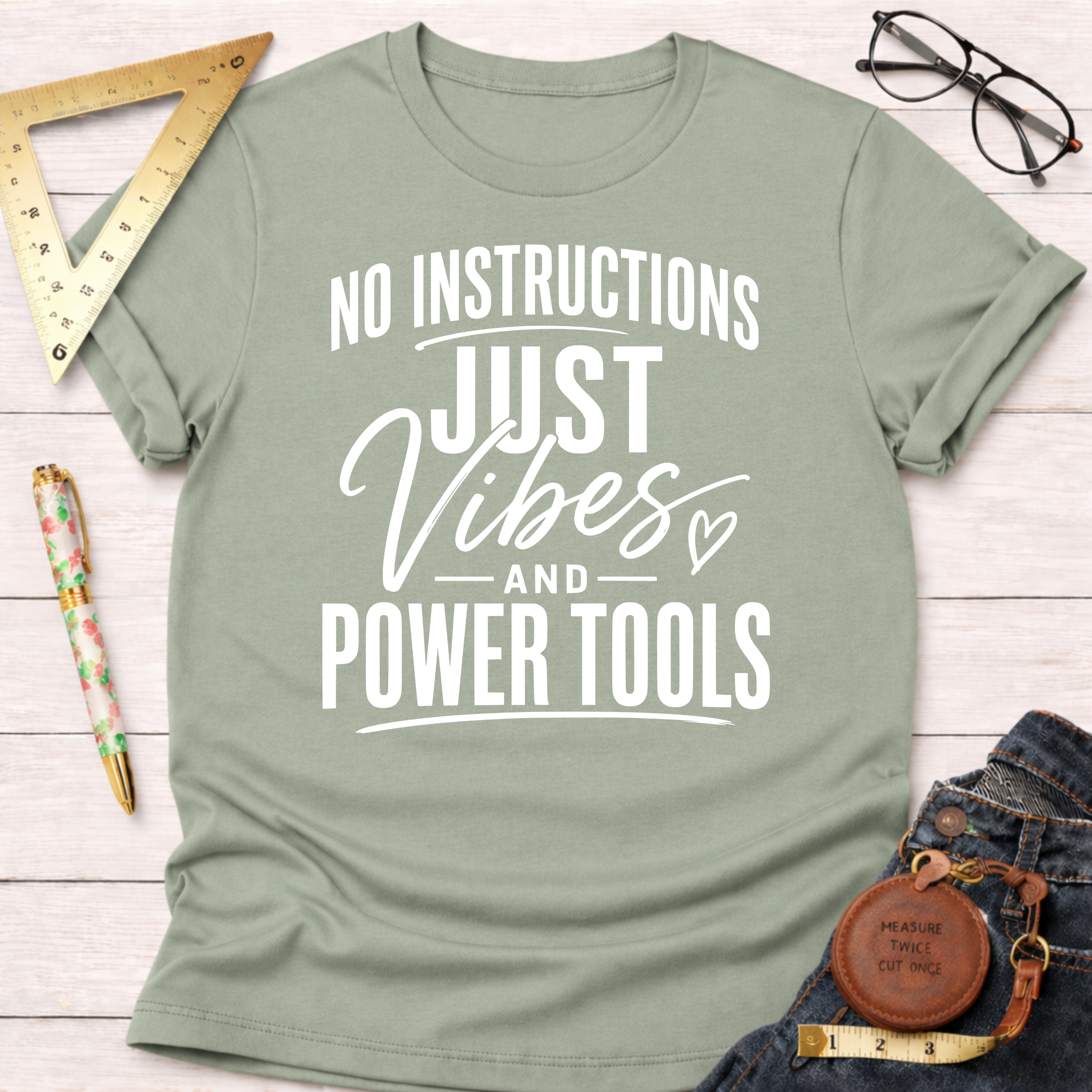Sage green t-shirt with "NO INSTRUCTIONS JUST VIBES AND POWER TOOLS" in white text.