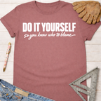 Women's funny woodworking graphic tee shirt for female woodworkers, makers, and DIY builders — Sawdust & Ponytails. Mauve cotton t-shirt with "DO IT YOURSELF so you know who to blame" in white text.
