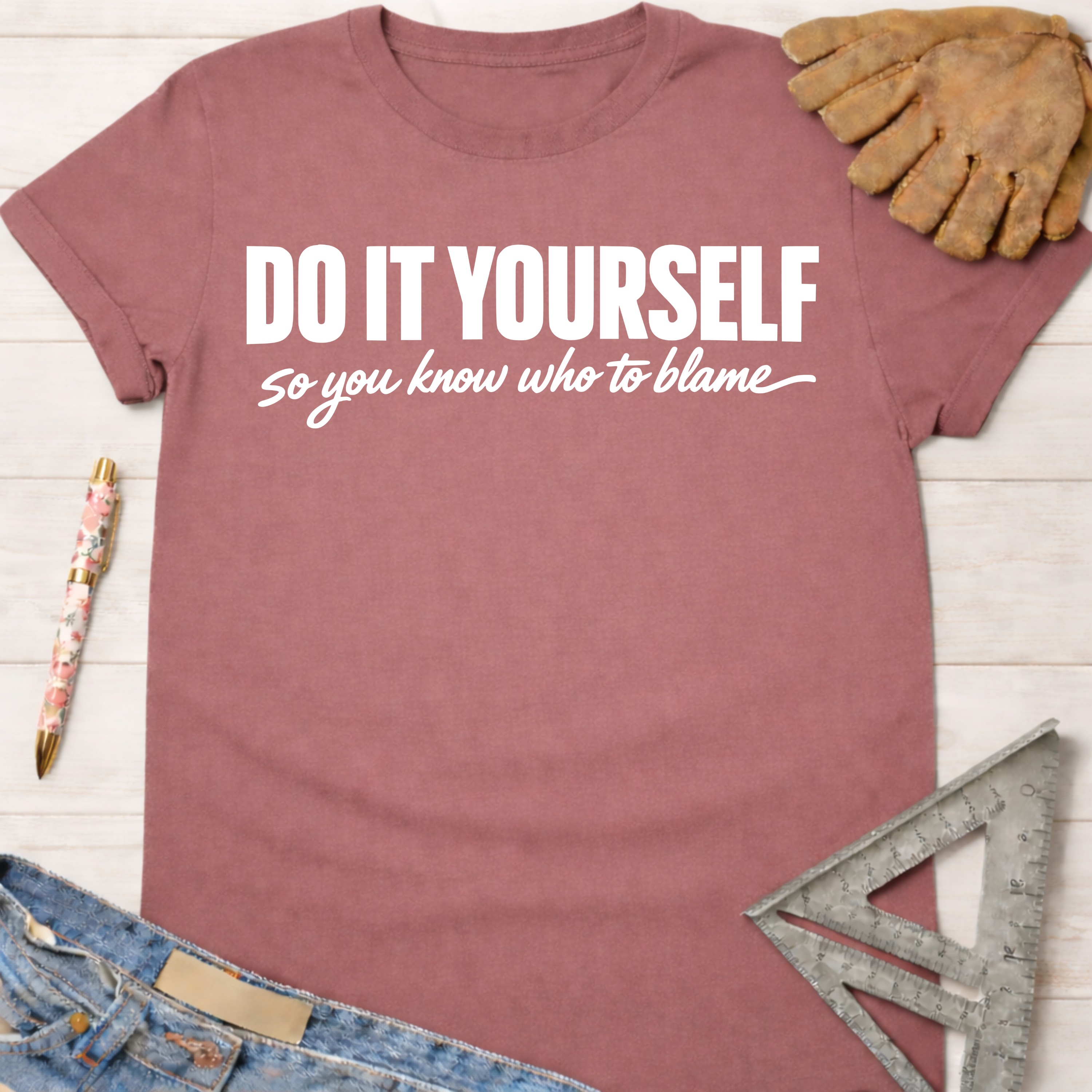 Women's funny woodworking graphic tee shirt for female woodworkers, makers, and DIY builders — Sawdust & Ponytails. Mauve cotton t-shirt with "DO IT YOURSELF so you know who to blame" in white text.