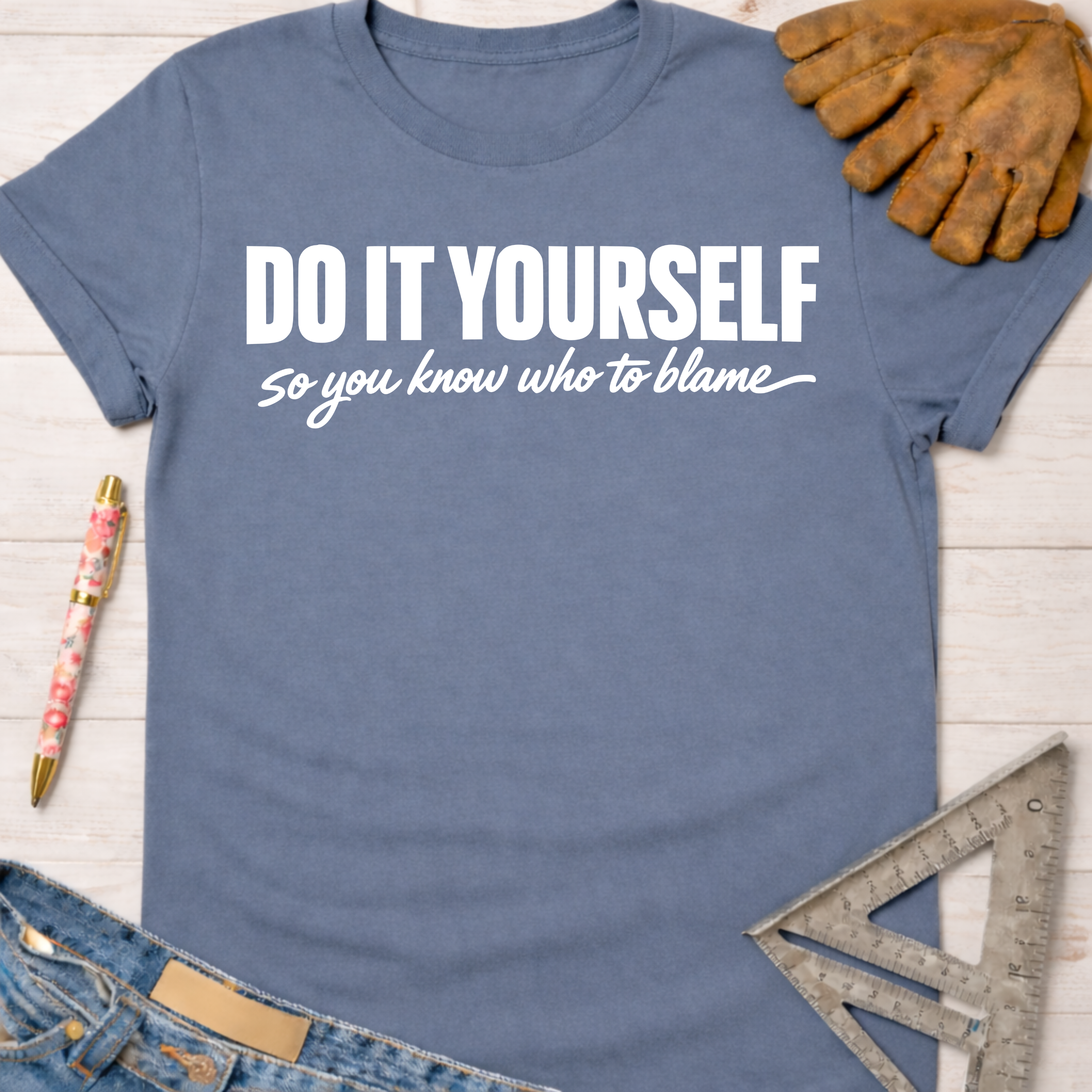 Women's funny woodworking graphic tee shirt for female woodworkers, makers, and DIY builders — Sawdust & Ponytails. Blue short-sleeve tee with "DO IT YOURSELF so you know who to blame" in white text.