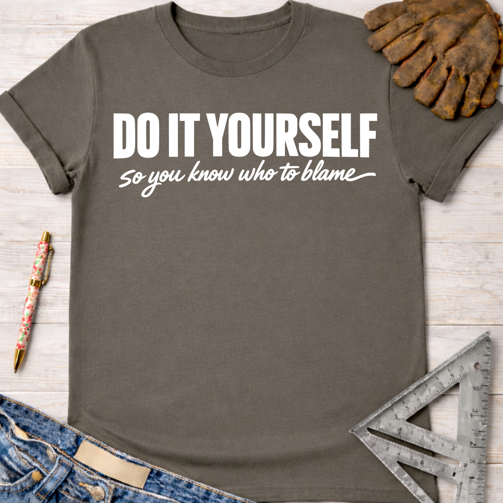 Women's funny woodworking graphic tee shirt for female woodworkers, makers, and DIY builders — Sawdust & Ponytails. Dark gray cotton t-shirt with "DO IT YOURSELF so you know who to blame" in white text.