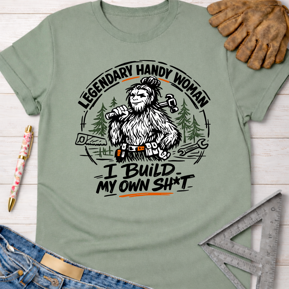 Women's funny woodworking graphic tee shirt for female woodworkers, makers, and DIY builders — Sawdust & Ponytails. Sage green cotton t-shirt with a Bigfoot "Legendary Handy Woman" graphic.