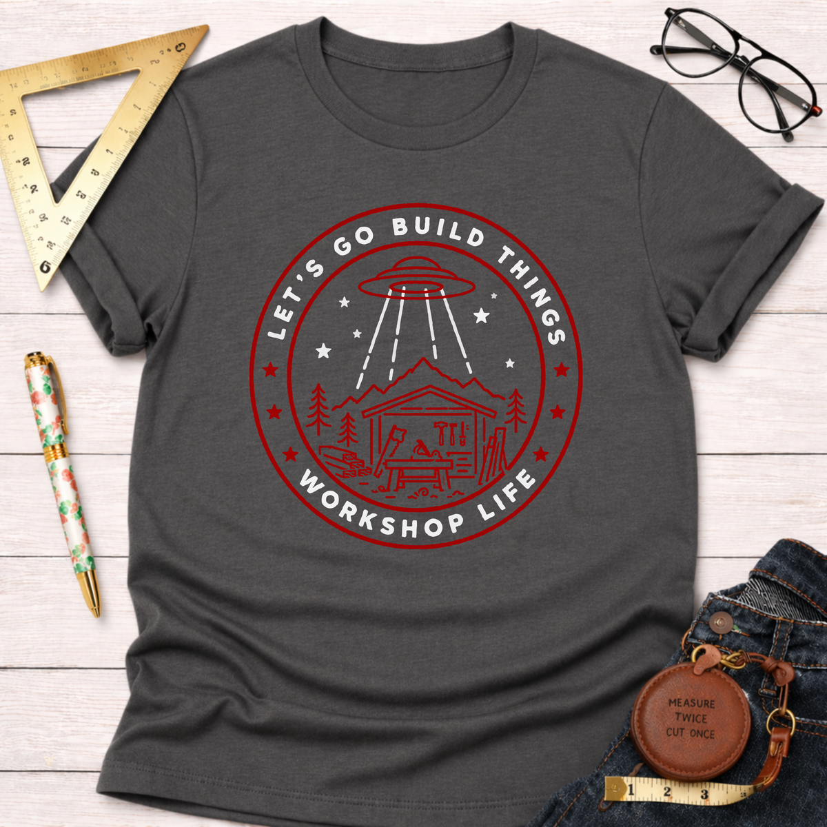 Charcoal gray "Let's Go Build Things Workshop Life" t-shirt with red graphic of a UFO beaming down on a workshop.