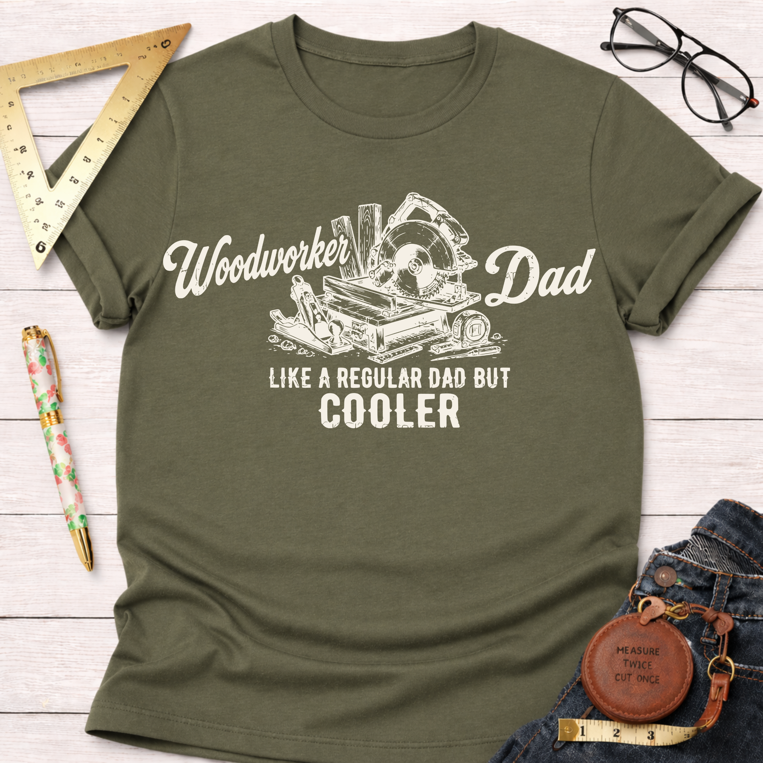 Olive green cotton t-shirt with "Woodworker Dad Like a Regular Dad But Cooler" text and tools graphic.