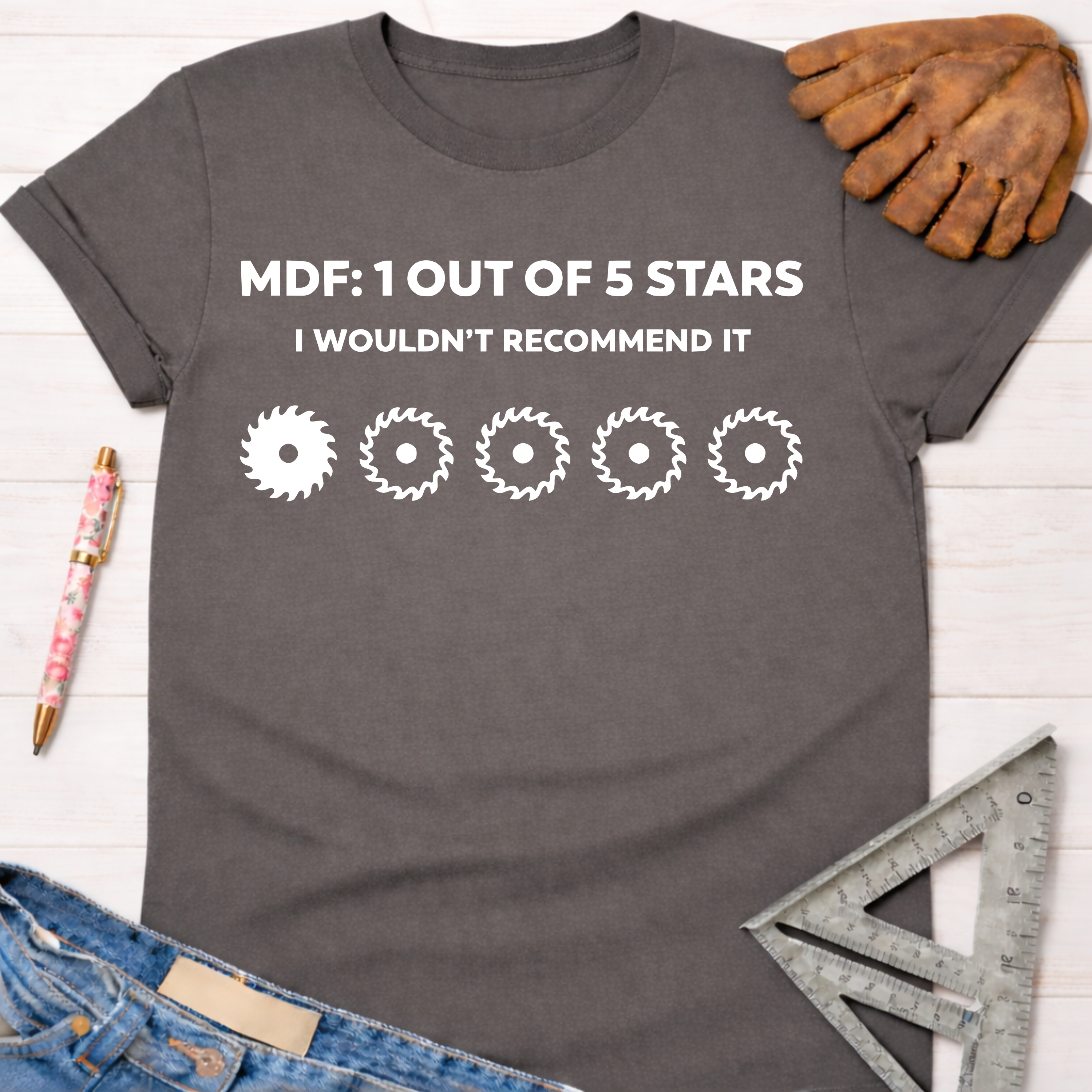 Women's funny woodworking graphic tee shirt for female woodworkers, makers, and DIY builders — Sawdust & Ponytails. Dark gray t-shirt with "MDF: 1 Out Of 5 Stars I Wouldn't Recommend It" and five saw blade icons.