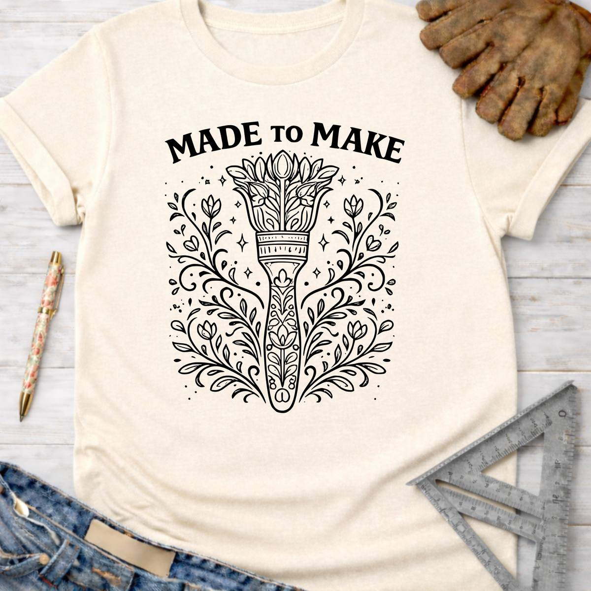 Women's funny woodworking graphic tee shirt for female woodworkers, makers, and DIY builders — Sawdust & Ponytails. Cream t-shirt with "MADE TO MAKE" and ornate floral torch design.